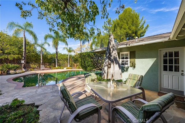 view of patio with a fenced in pool, outdoor dining area, and fence