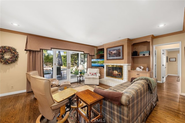 living room with wood-type flooring, crown molding, a tile fireplace, and french doors