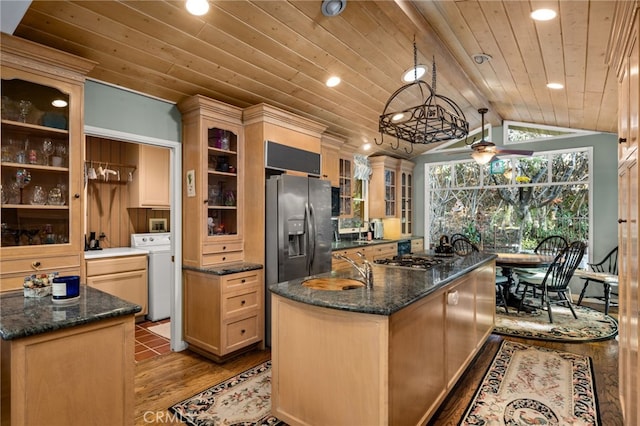 kitchen with lofted ceiling with beams, washer / dryer, a center island with sink, wood ceiling, and appliances with stainless steel finishes