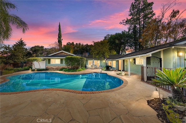 pool at dusk featuring a patio