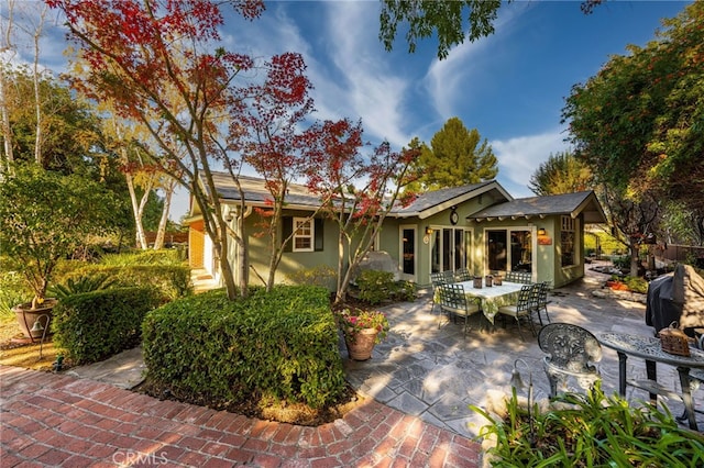 rear view of house featuring outdoor dining space, a patio area, and stucco siding