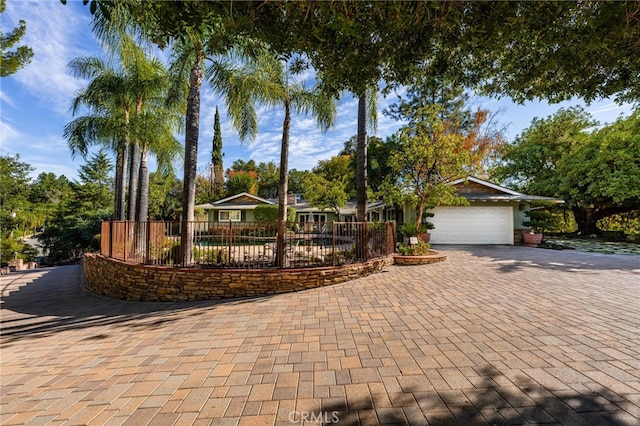 ranch-style home featuring decorative driveway, fence, and a garage