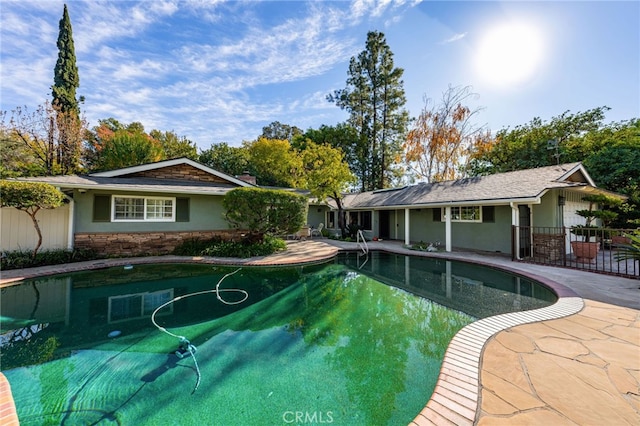 outdoor pool featuring fence and a patio area