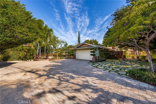 view of home's exterior with a garage, fence, and decorative driveway