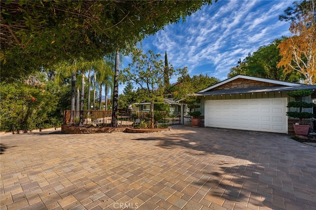 garage with decorative driveway and fence