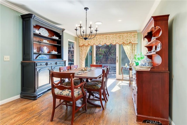 dining space with a chandelier, crown molding, light wood-type flooring, and baseboards