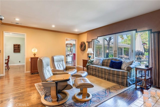 living room with french doors, baseboards, light wood-style floors, and ornamental molding