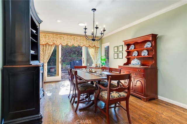 dining room featuring light wood-type flooring, baseboards, an inviting chandelier, and crown molding