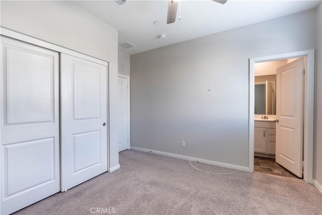 unfurnished bedroom featuring connected bathroom, light carpet, a closet, and ceiling fan