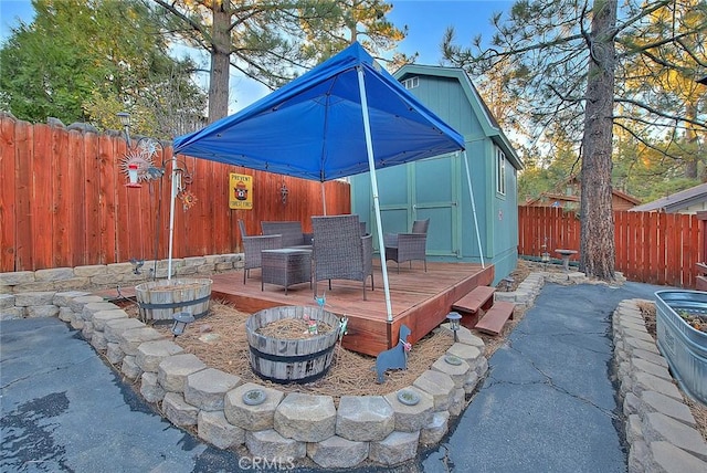 view of patio / terrace featuring a wooden deck, a fire pit, and a shed