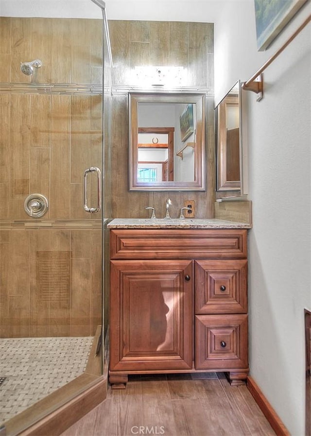 bathroom with vanity, a shower with shower door, and wood-type flooring