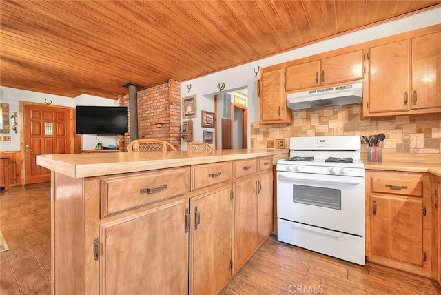 kitchen with white gas stove, wood ceiling, under cabinet range hood, and a peninsula