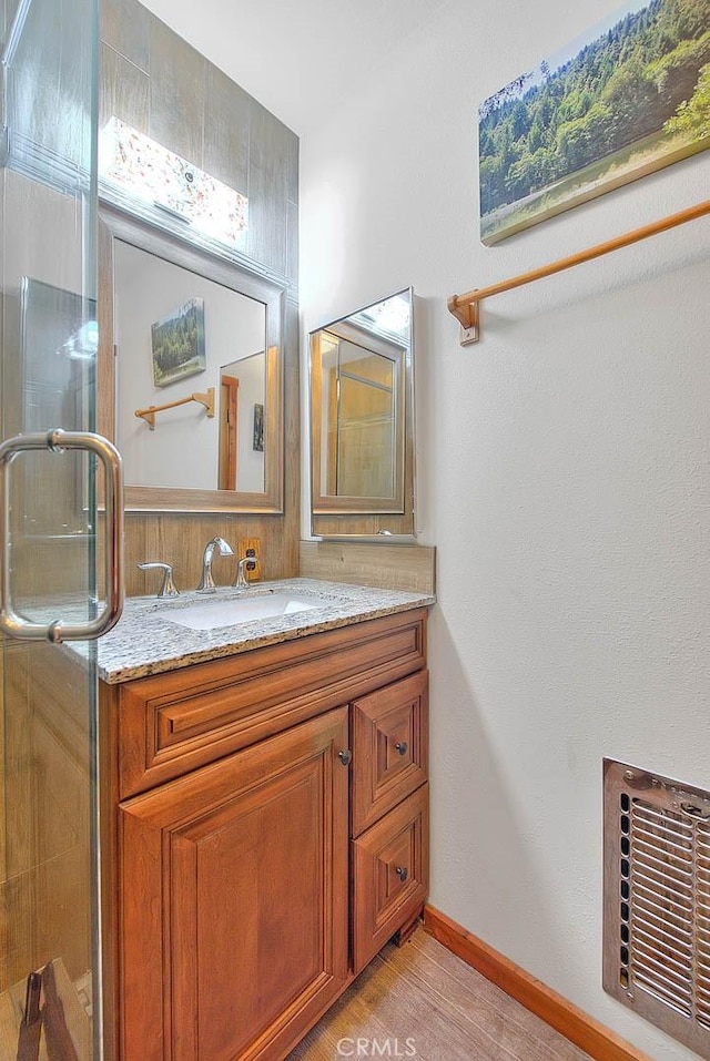 bathroom with vanity, a shower with door, and hardwood / wood-style floors