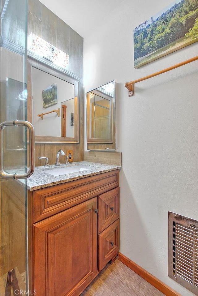 bathroom featuring a shower stall, wood finished floors, visible vents, vanity, and baseboards