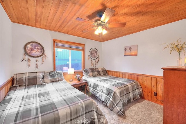 bedroom featuring a ceiling fan, wooden walls, a wainscoted wall, carpet, and wooden ceiling