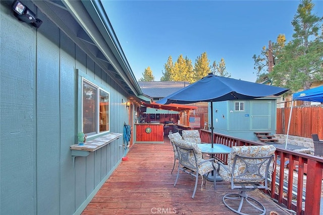 wooden terrace with an outbuilding, a shed, and outdoor dining area