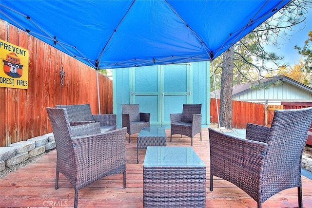 view of patio / terrace featuring a storage unit, an outbuilding, an outdoor hangout area, and a fenced backyard