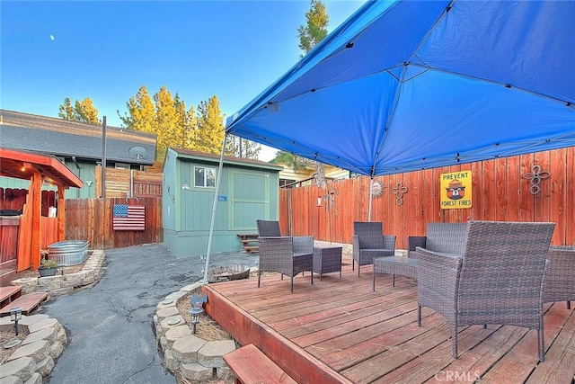 wooden terrace with fence, a storage unit, and an outbuilding