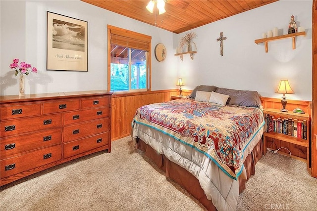 bedroom with wainscoting, wooden ceiling, wood walls, and light colored carpet