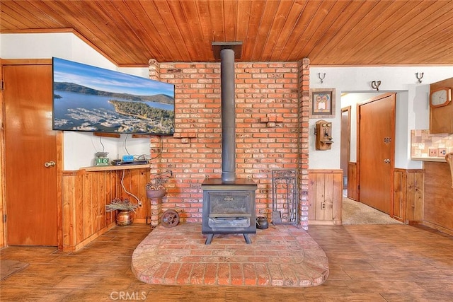 unfurnished living room featuring wooden ceiling, light hardwood / wood-style flooring, a wood stove, and wood walls