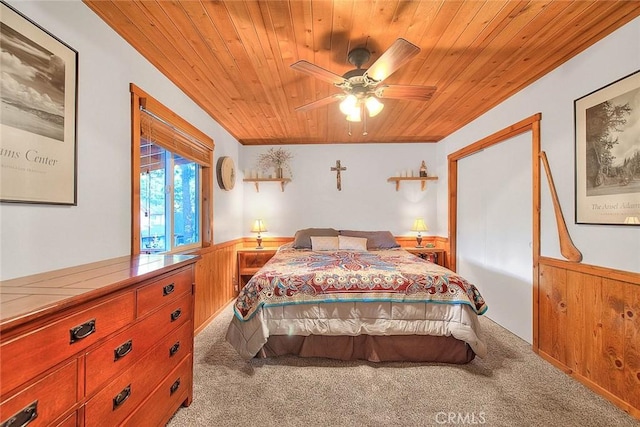 bedroom with carpet floors, a wainscoted wall, wood ceiling, and a ceiling fan