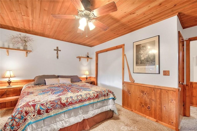 carpeted bedroom with wooden walls, a ceiling fan, wood ceiling, and wainscoting