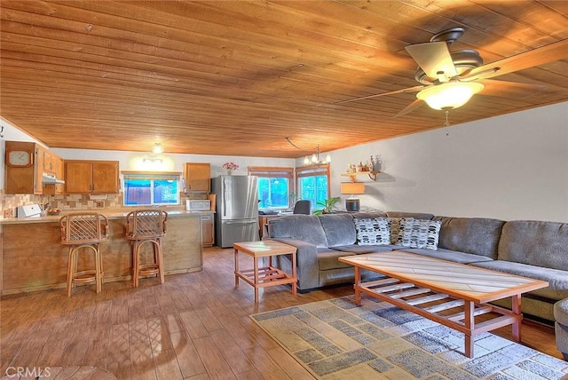 living room with hardwood / wood-style flooring, ceiling fan with notable chandelier, and wood ceiling