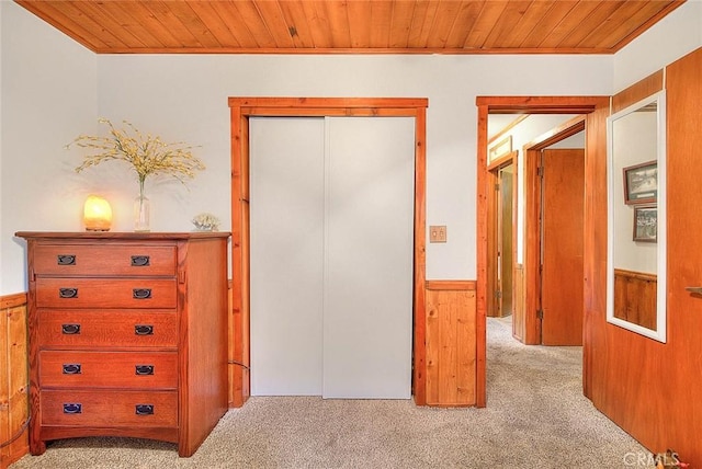 unfurnished bedroom with ornamental molding, light colored carpet, wooden ceiling, and wood walls