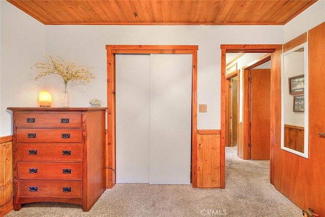 bedroom featuring wainscoting, wooden ceiling, light carpet, and wooden walls