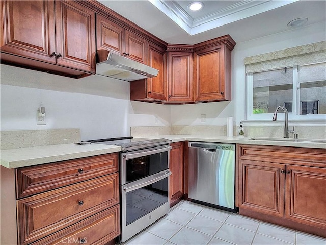 kitchen with sink, stainless steel appliances, a raised ceiling, light tile patterned flooring, and ornamental molding