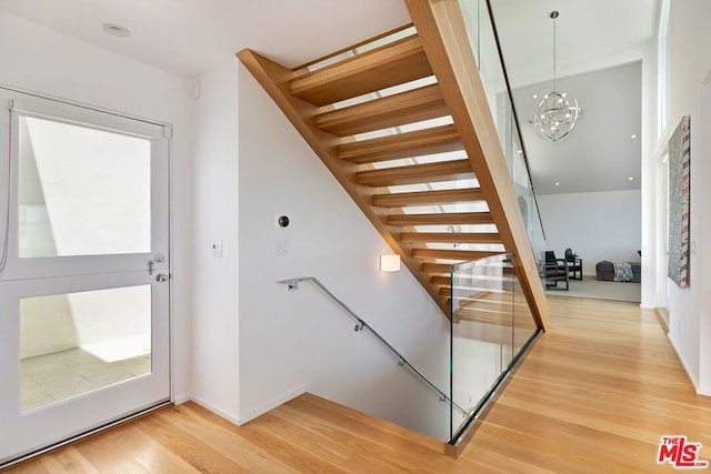 stairway featuring hardwood / wood-style flooring and an inviting chandelier