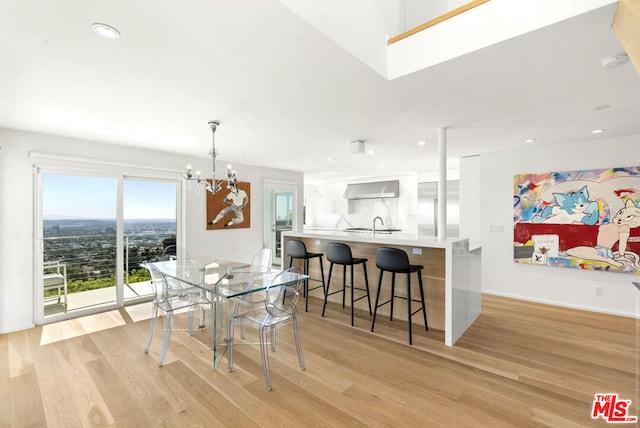 dining area with sink, light hardwood / wood-style floors, and an inviting chandelier