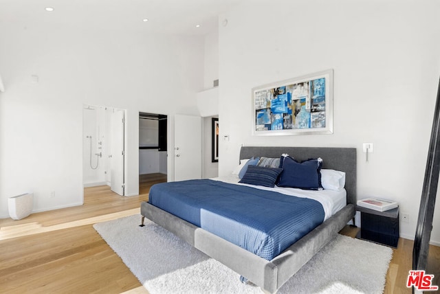 bedroom featuring wood-type flooring and a high ceiling