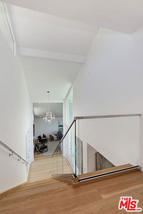 staircase with hardwood / wood-style floors, a healthy amount of sunlight, lofted ceiling, and a notable chandelier