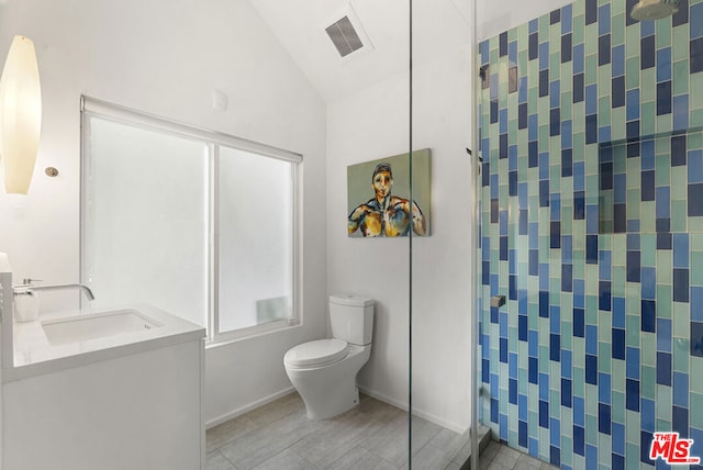 bathroom with toilet, vanity, tile patterned flooring, and vaulted ceiling