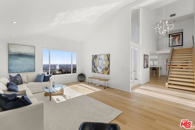 living room with high vaulted ceiling, wood-type flooring, and a notable chandelier