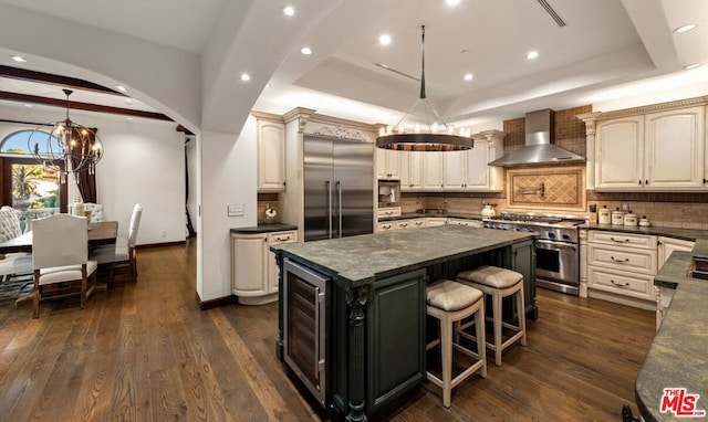 kitchen featuring built in appliances, wall chimney exhaust hood, dark hardwood / wood-style flooring, and backsplash