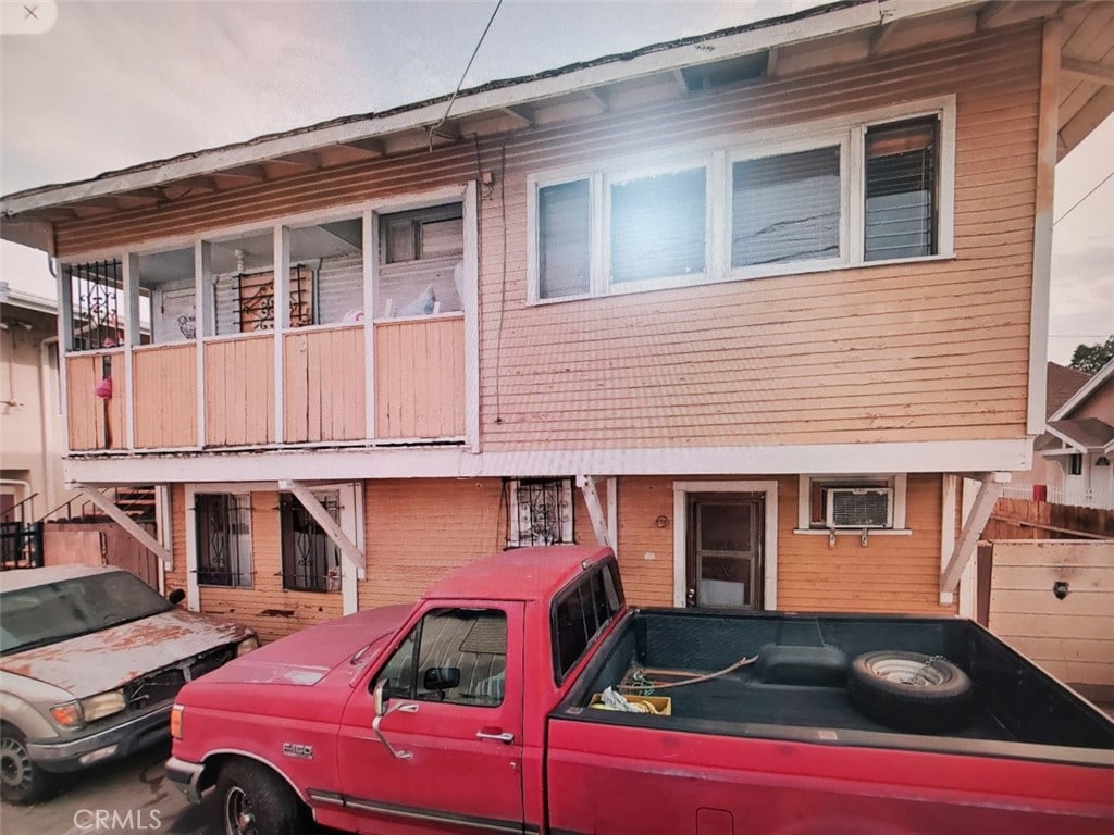 view of front of property with a balcony and a wall unit AC