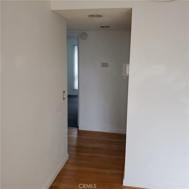 hallway with wood-type flooring and a textured ceiling