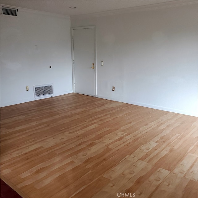 empty room featuring light wood-type flooring and crown molding