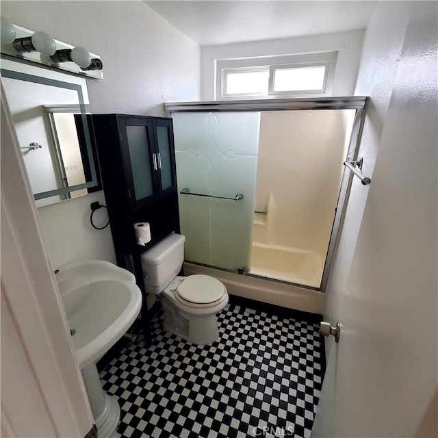 full bathroom featuring combined bath / shower with glass door, toilet, and sink