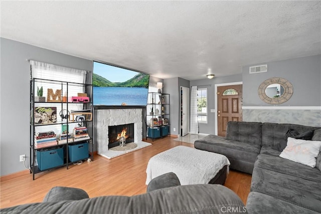 living room featuring a stone fireplace, hardwood / wood-style floors, and a textured ceiling