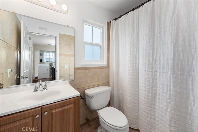 bathroom with vanity, toilet, and tile walls