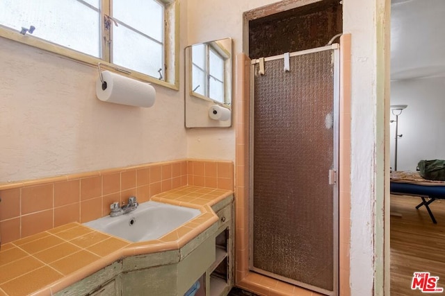 bathroom featuring sink, an enclosed shower, and hardwood / wood-style flooring