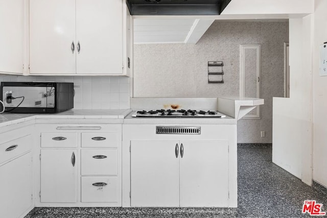 kitchen with white cabinets, white gas stovetop, backsplash, and extractor fan