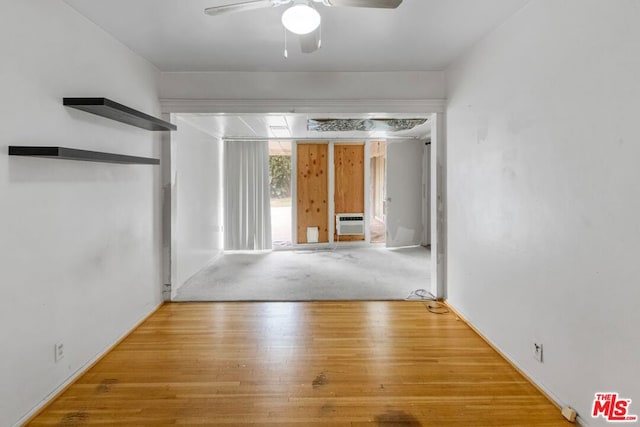 unfurnished room with light hardwood / wood-style floors, a wall unit AC, and ceiling fan