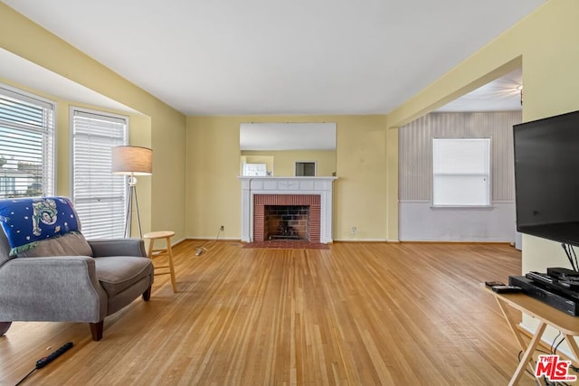 living room with light wood-type flooring and a brick fireplace