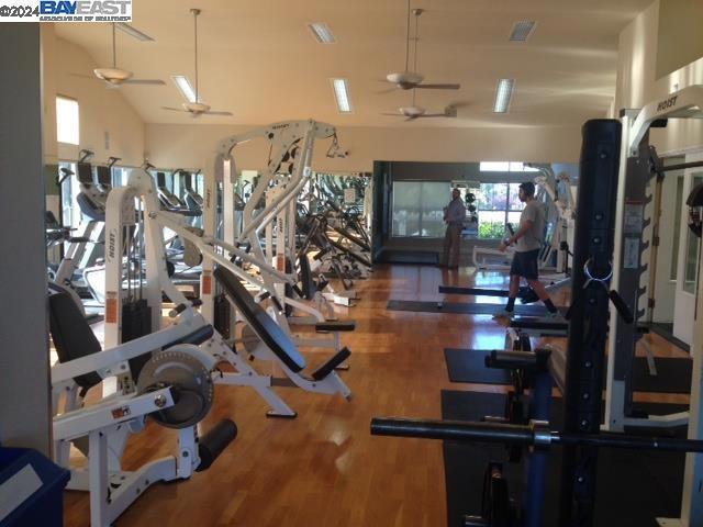 gym with hardwood / wood-style floors, high vaulted ceiling, and ceiling fan