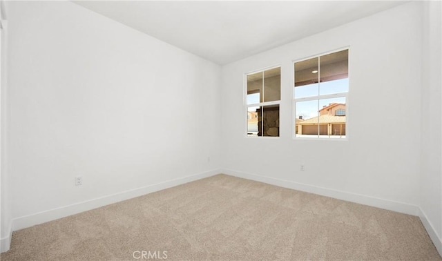 unfurnished room featuring baseboards and light colored carpet