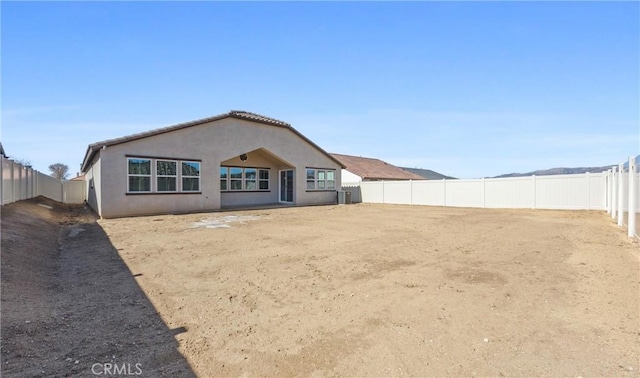 rear view of house with a fenced backyard and stucco siding